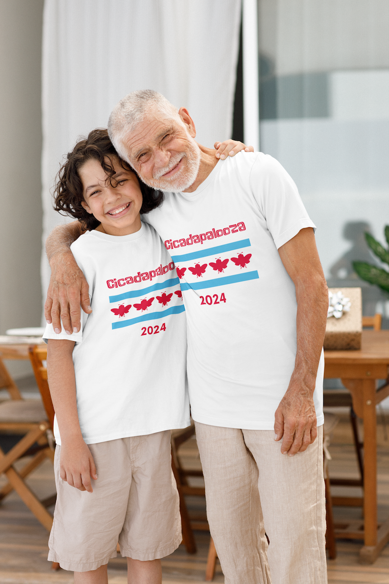 A 10 year old boy embraces his grandfather. They are smiling and are wearing white t-shirts with red text saying, "Cicadapalooza." Also, the Chicago flag with the stars replaced by cute, red cicadas.